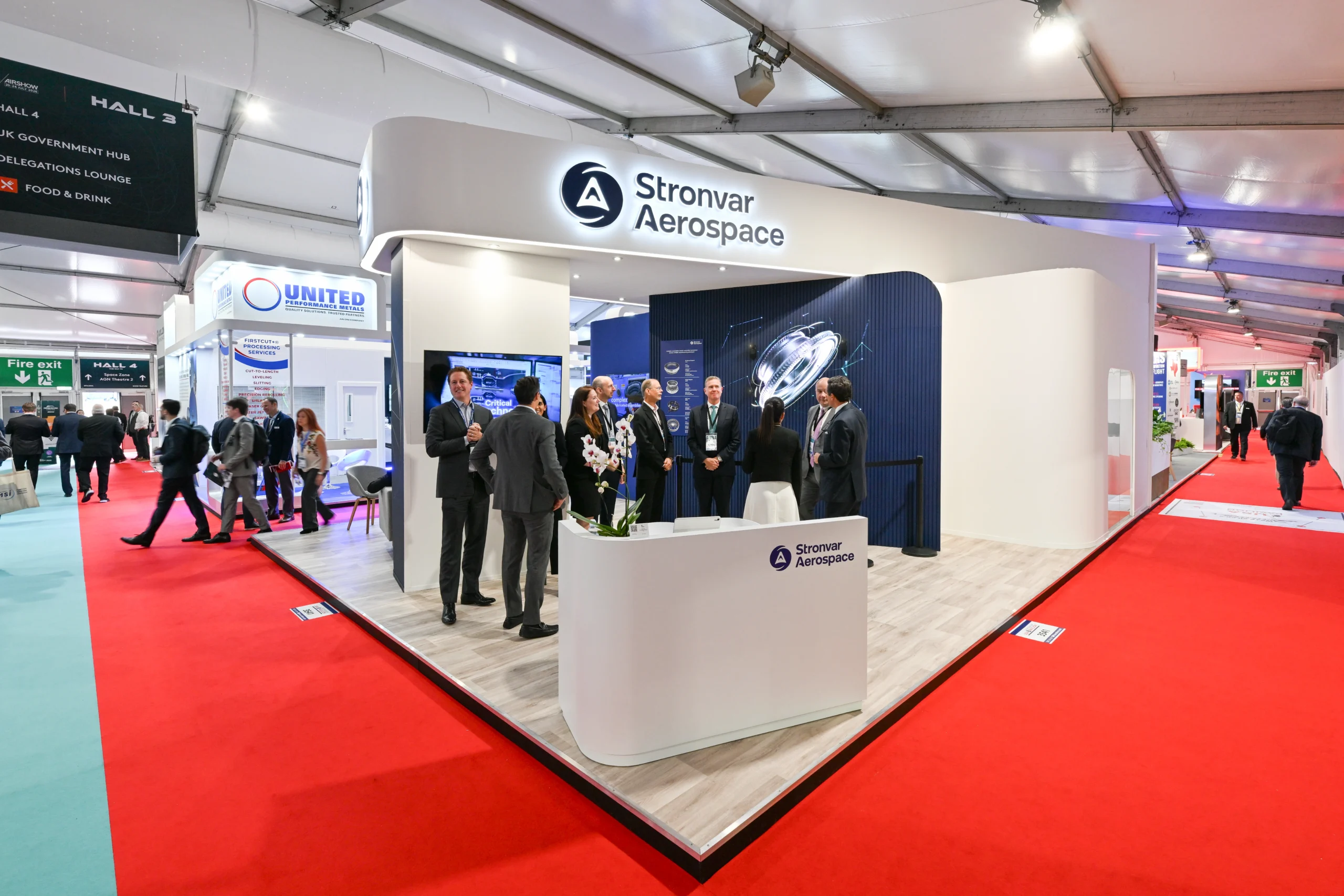 Stronvar Aerospace exhibition stand with curved white branding, reception desk and meeting area at Farnborough Airshow 2026